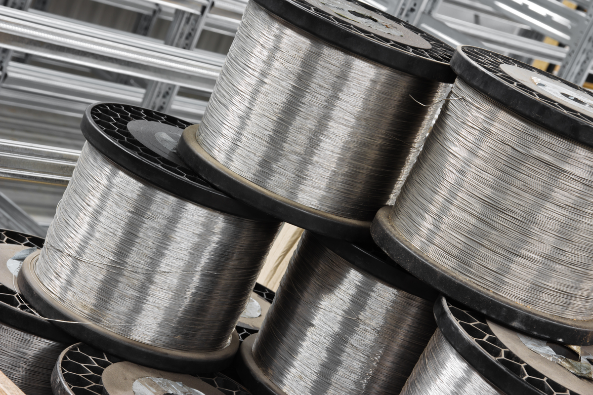 Coils of stainless steel wire are stacked in a warehouse.